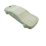 A pale mint green car-shaped silicone teether with raised stud details around the edges, resting on a white marble-patterned surface.