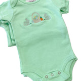Green baby onesie with Easter design on a marble surface