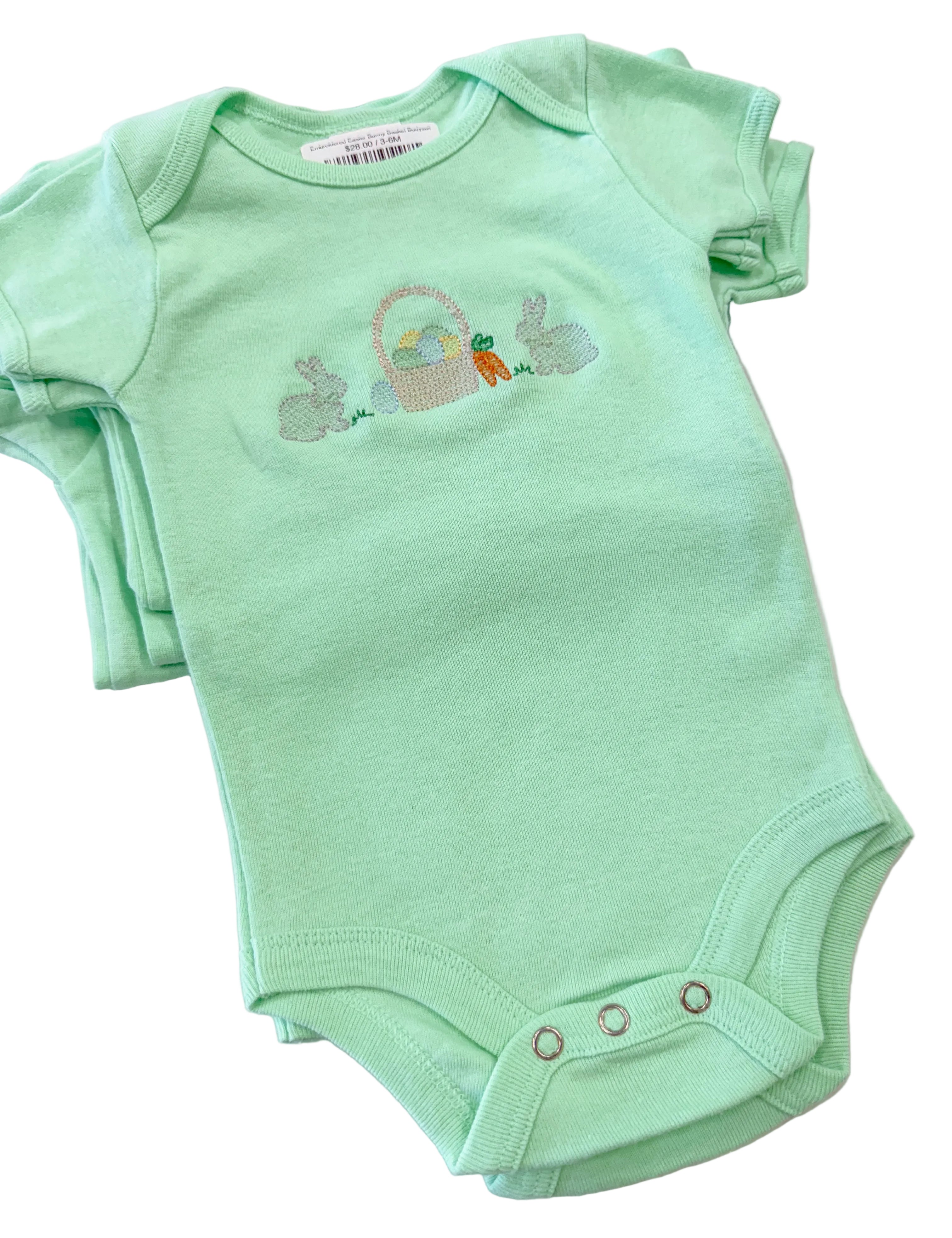 Green baby onesie with Easter design on a marble surface
