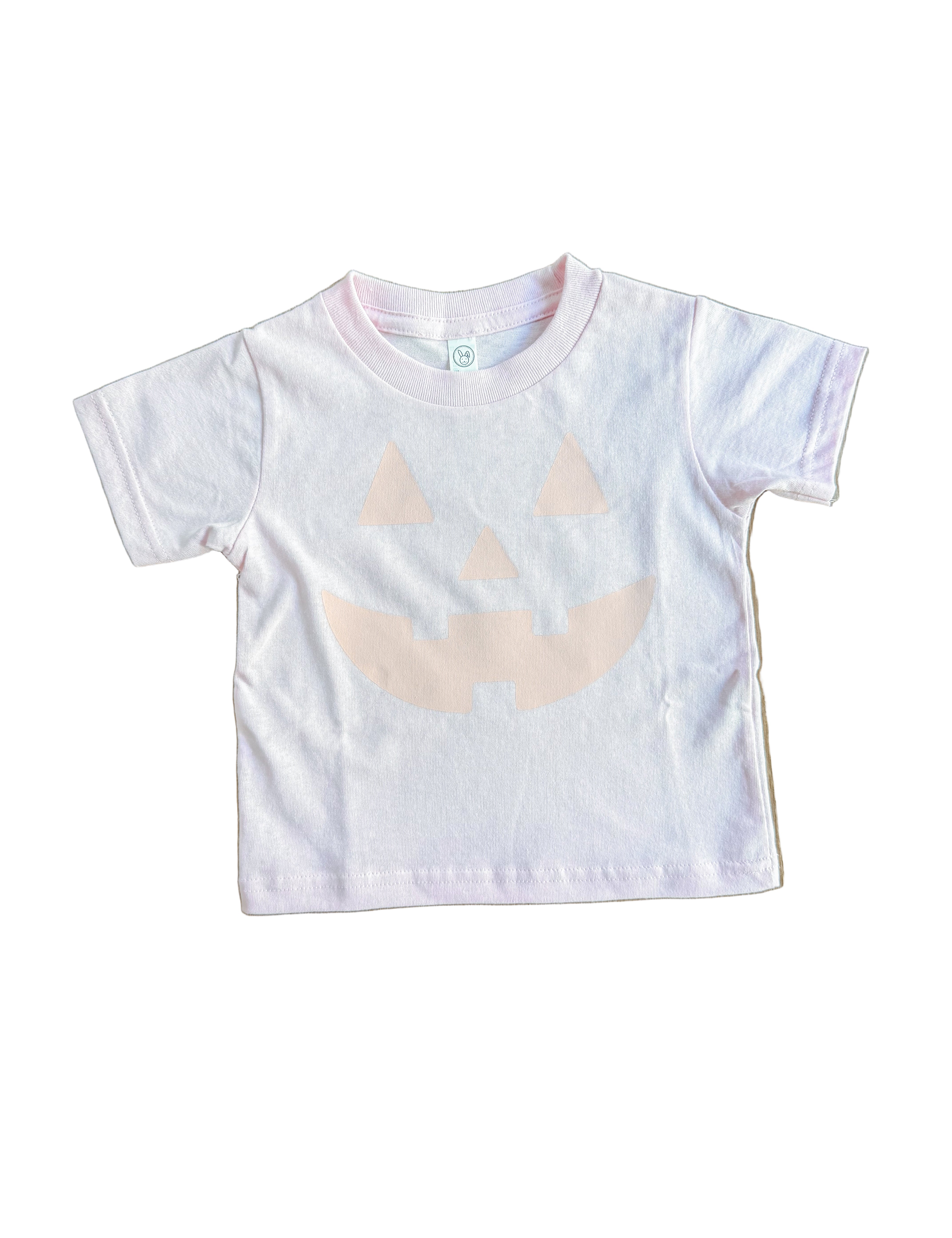 pink t-shirt with a beige abstract design on a wooden surface