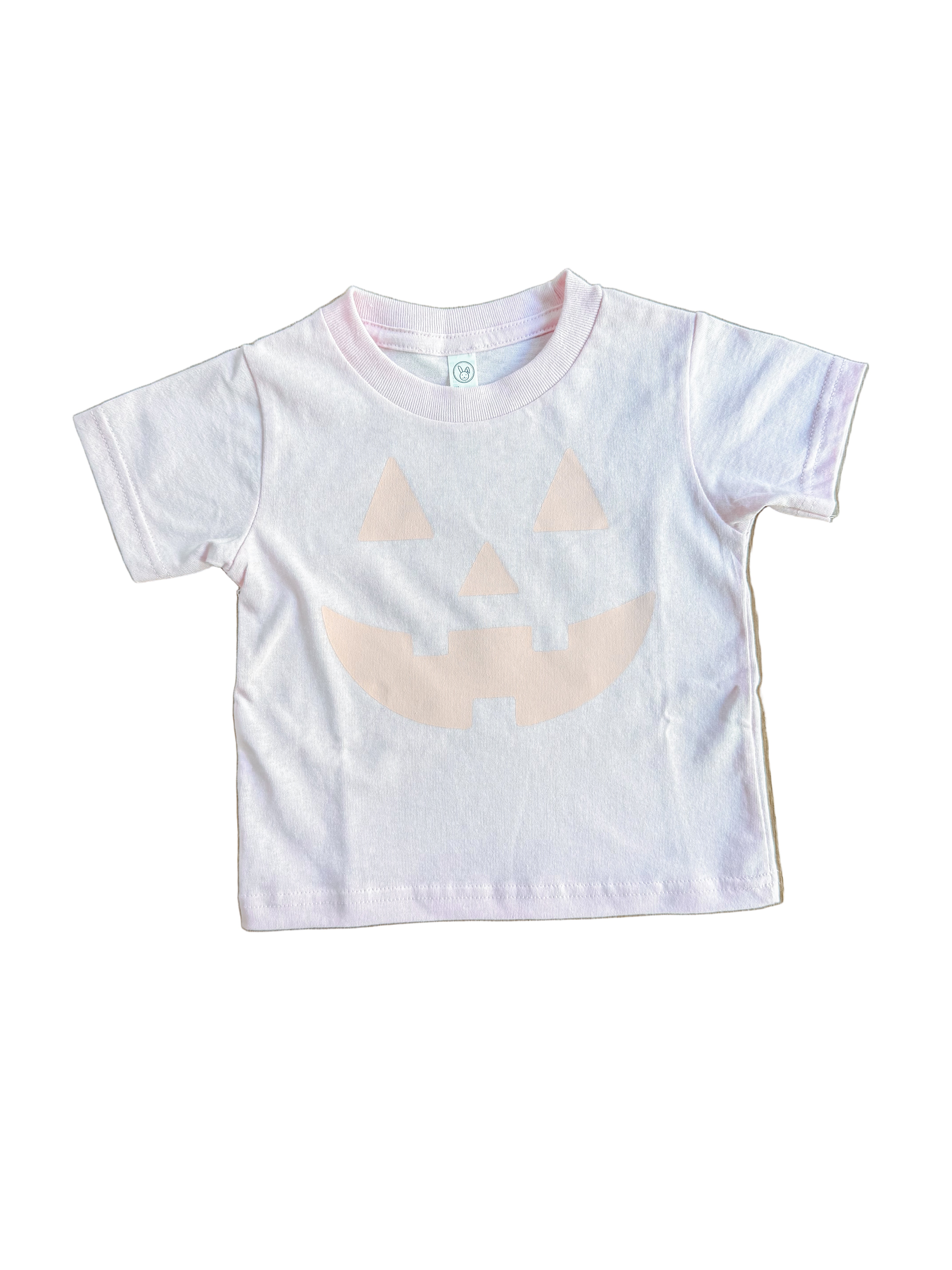 pink t-shirt with a beige abstract design on a wooden surface