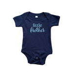 Navy blue baby onesie with 'little brother' text on a textured surface