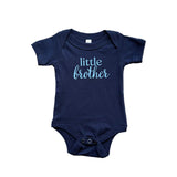 Navy blue baby onesie with 'little brother' text on a textured surface