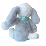 Gray plush bunny with a green bow tie on a white surface in a store setting.