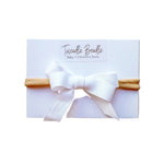 White headband with a bow on a white card, branded 'Twiddle Beadle'.