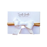 White headband with a bow on a white card, branded 'Twiddle Beadle'.
