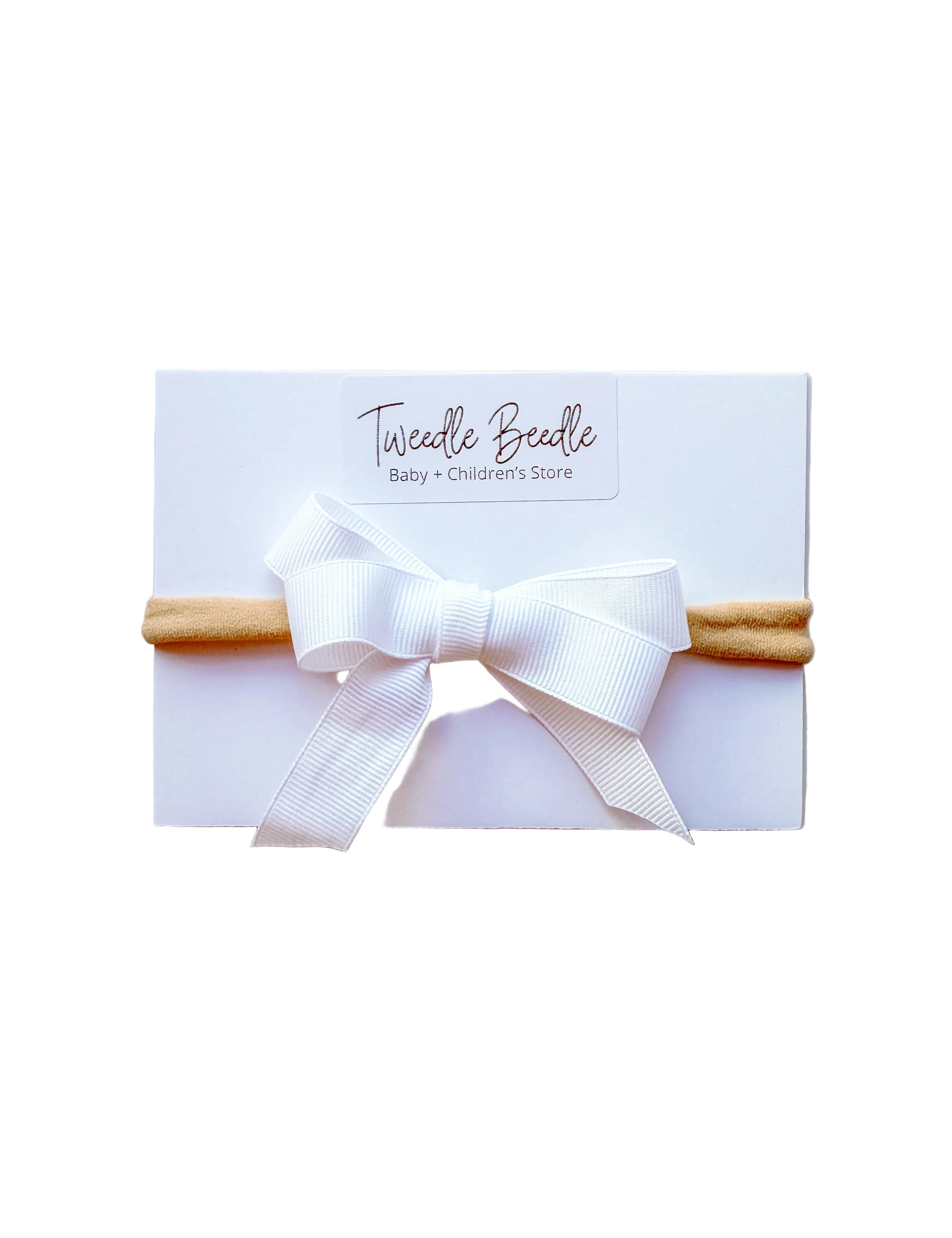 White headband with a bow on a white card, branded 'Twiddle Beadle'.
