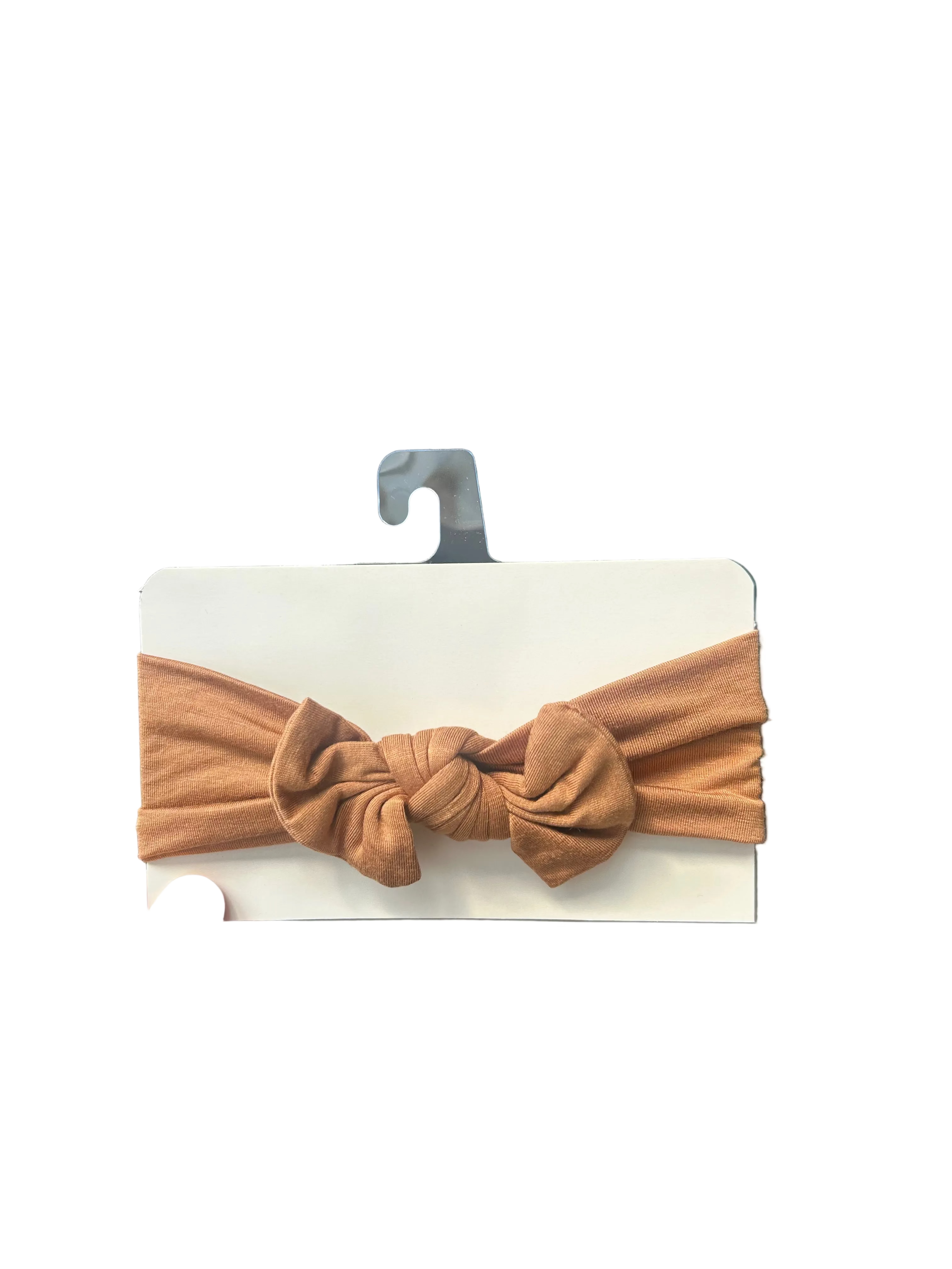 Brown knotted headband on a card held by a hand with a store interior in the background