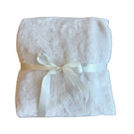 Folded white towel with a ribbon on a wooden surface