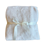 Folded white towel with a ribbon on a wooden surface
