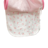 Baby bib with pink trim held up against a store display with various baby items.