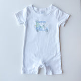 A white short-sleeve baby romper with a small light blue and green golf cart graphic on the chest, laid flat on a light gray background.
