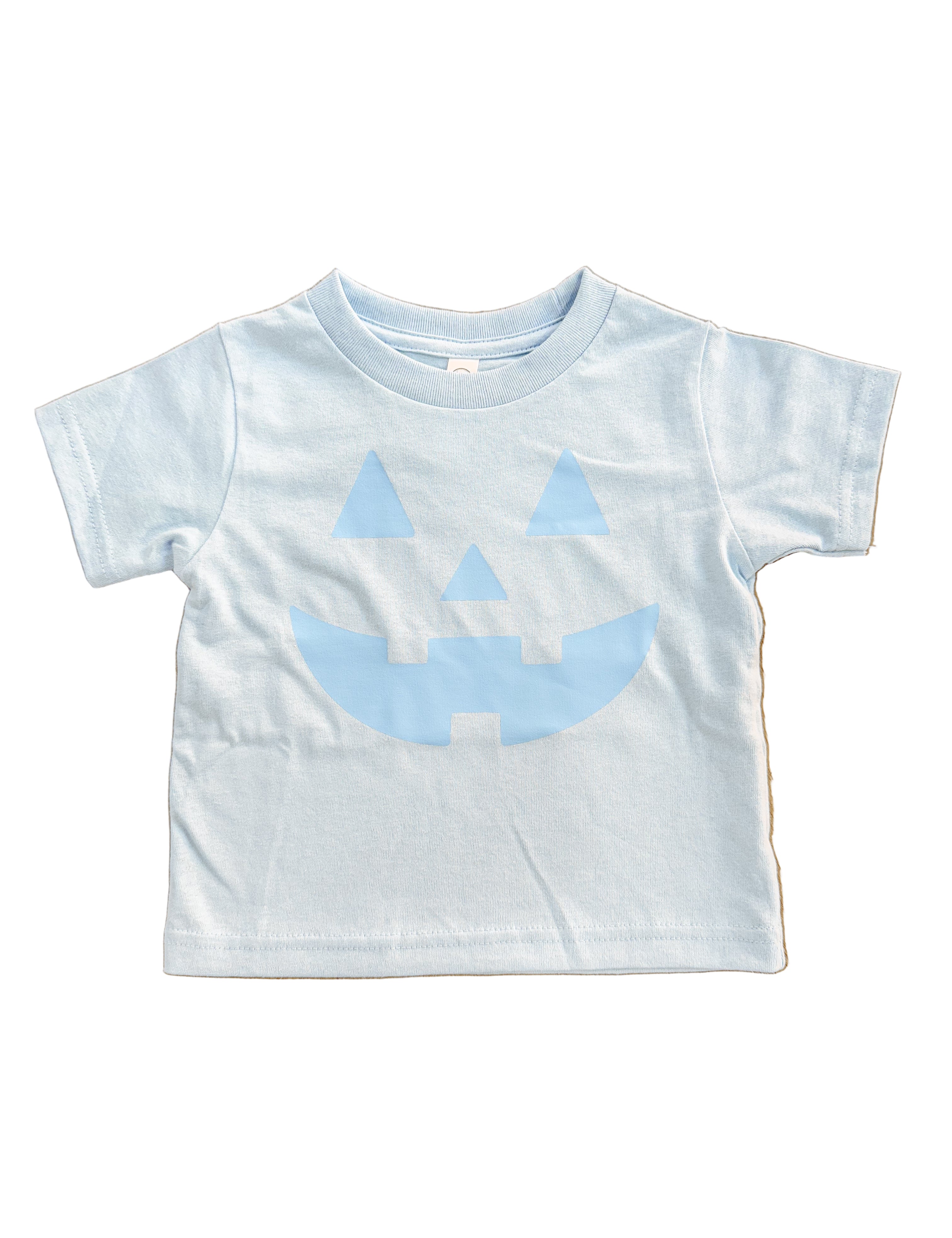 light blue kids  t-shirt with blue jack-o'-lantern design on a wooden floor