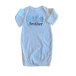 White baby onesie with 'little brother' text on a wooden floor