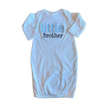White baby onesie with 'little brother' text on a wooden floor