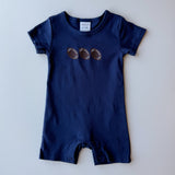 A navy blue baby romper with three embroidered footballs on the chest, laid flat against a light gray background.