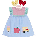 Children's dress with appliqués of a school bus, apple, and ice cream cone on a wooden surface.