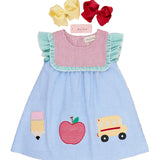 Children's dress with appliqués of a school bus, apple, and ice cream cone on a wooden surface.