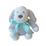 Plush dog toy with a blue bow on a white surface in a store setting